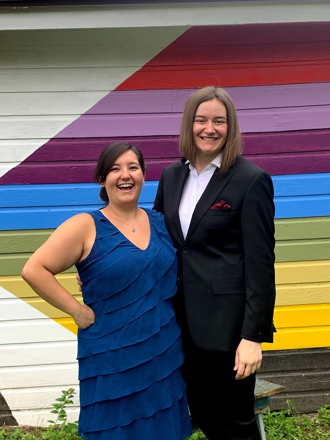 Aimee Oda'16 and Melissa Korniejczuk'17 pose in front of a rainbow wall.