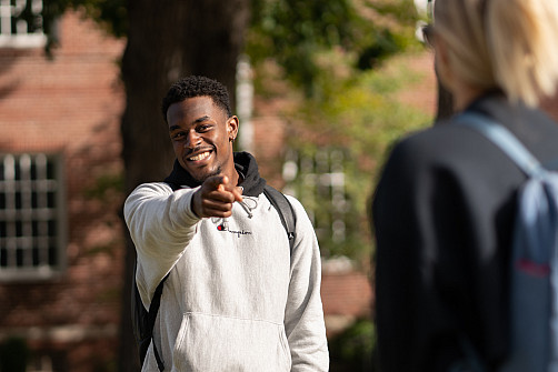 Beloit student outside, pointing and smiling at class mate.