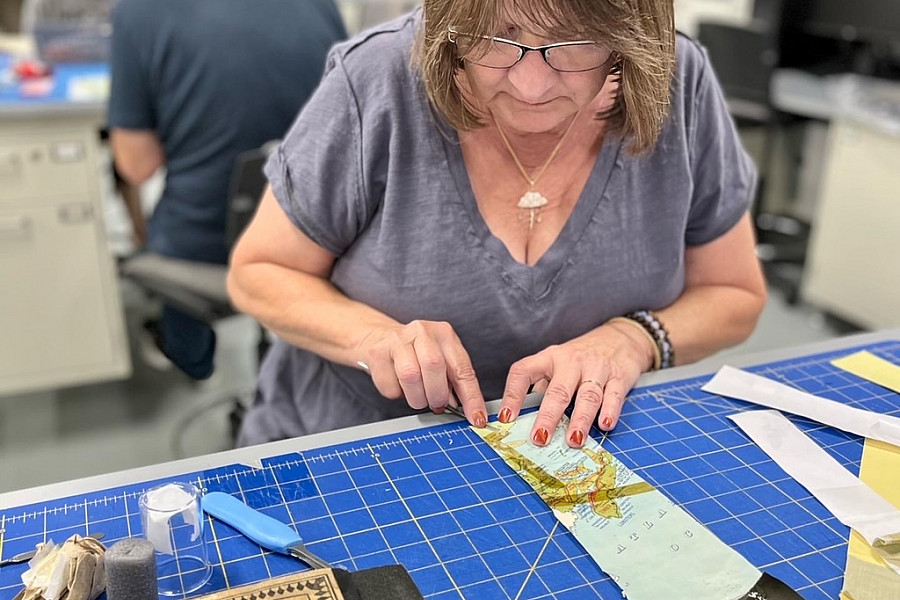 Introduction to Paper Conservation participant practicing adhesive removal.