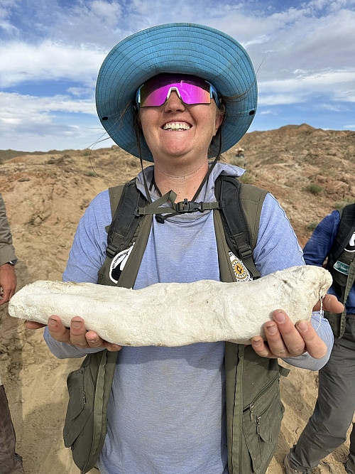 Kiernyn '16poses with a cast of a small dinosaur fossil.