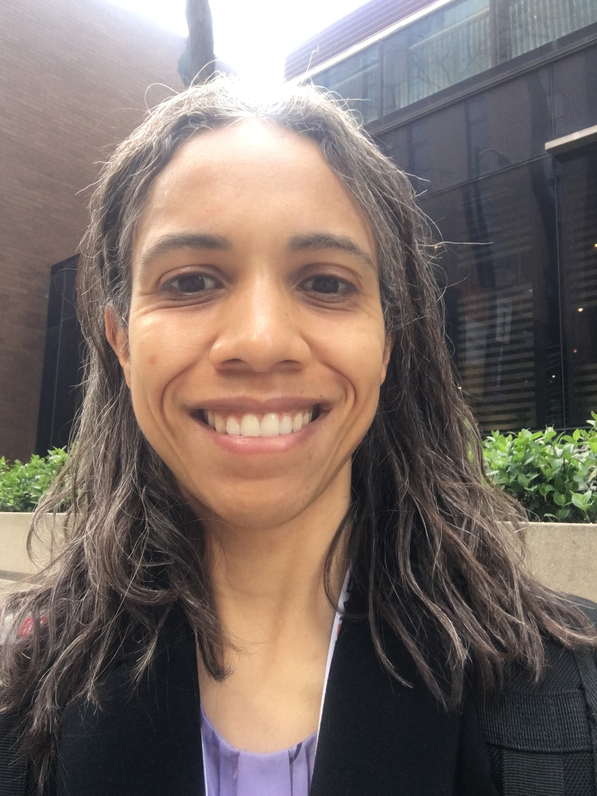 Portrait photo of a Black woman with shoulder length dark hair, smiling for the camera.