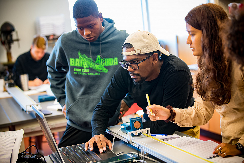 A group of students collaborate on a physics project in class.