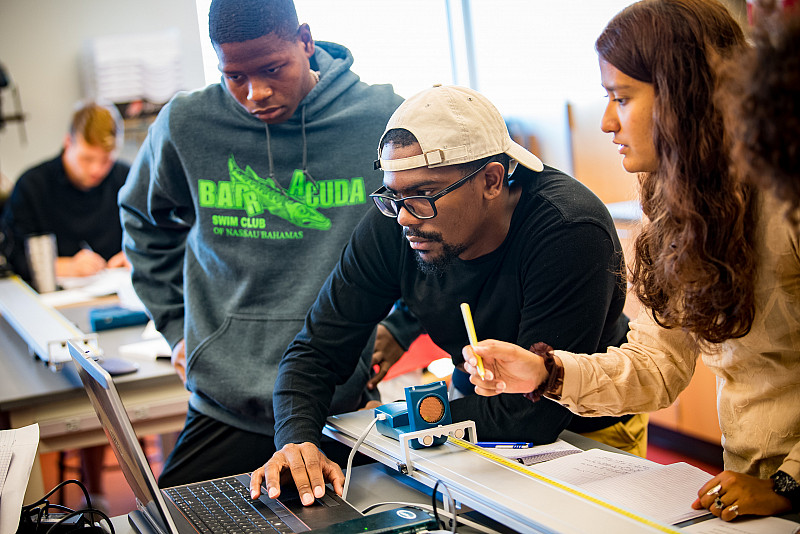 A group of students collaborate on a physics project in class.