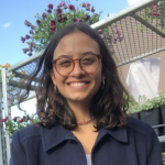 Maria Elvira Lopez’21 standing in front of potted plants