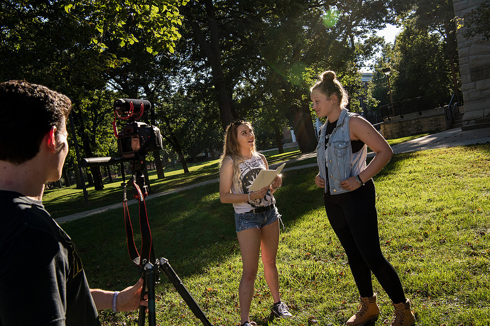 Two students practice an on-camera interview, while a third manages the camera.