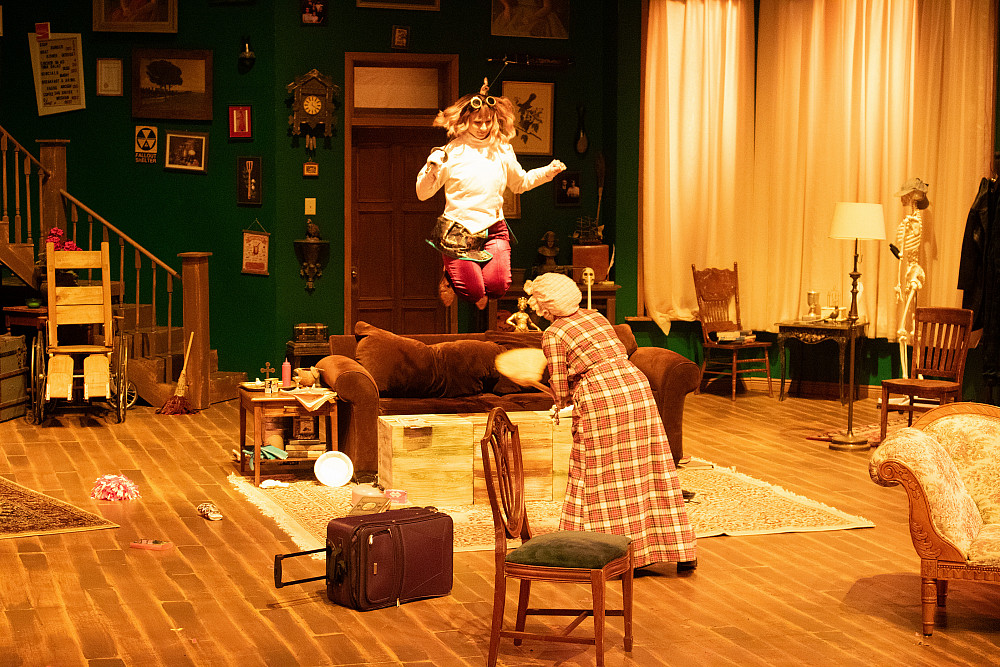 Ms. Holmes jumping on the couch while Ms. Watson tries to tidy up around her.