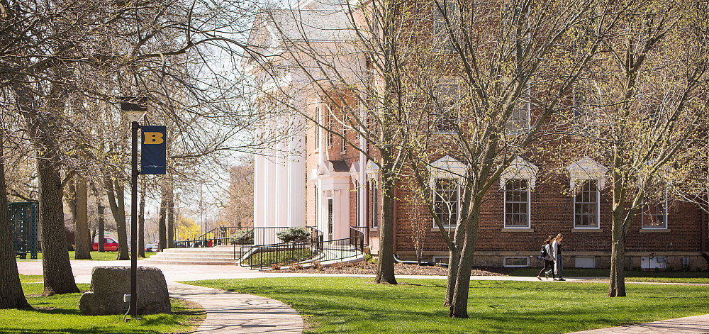 A view of Middle College in spring, trees budding with new leaves.