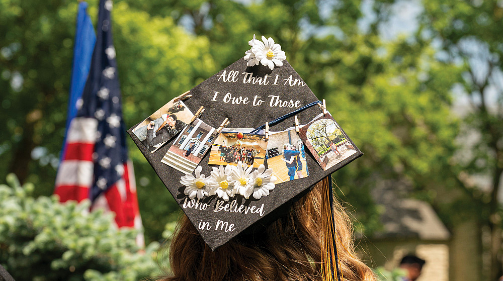 A graduation cap with a string of photos, All that I am I Owe to those who believes in me