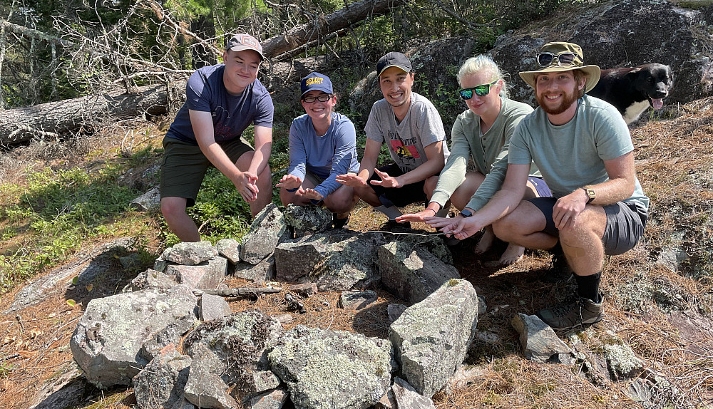 Students enrolled in the Writing Wilderness course pretend to warm their hands over an imaginary fire. Campfires were not allowed in summ...