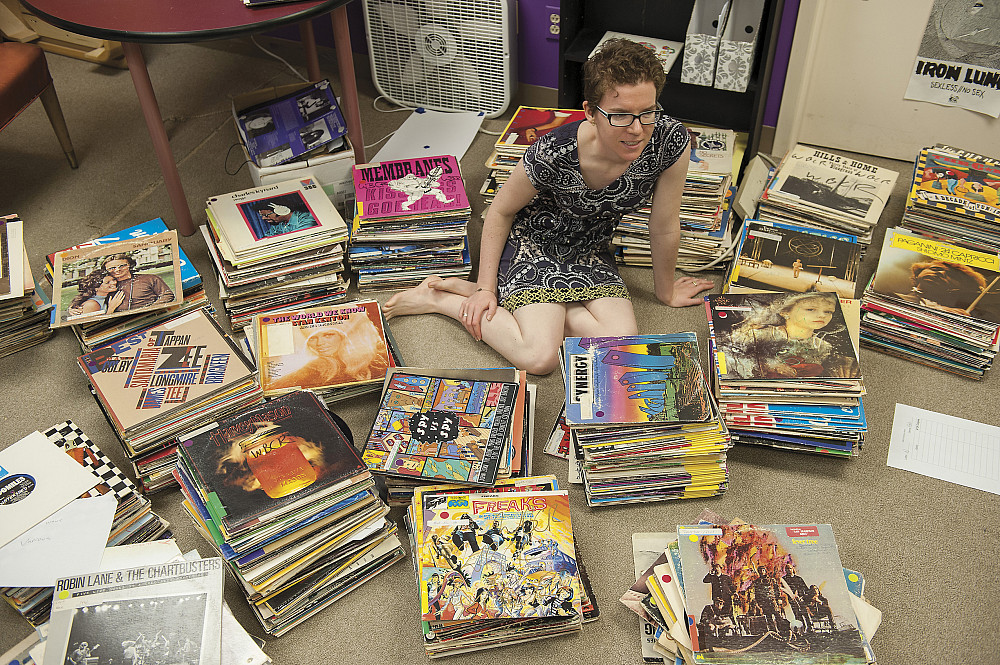 Station manager Nora Kane'16 holds up one of WBCR's many classic albums in the radio station's graffiti-covered storage ro...
