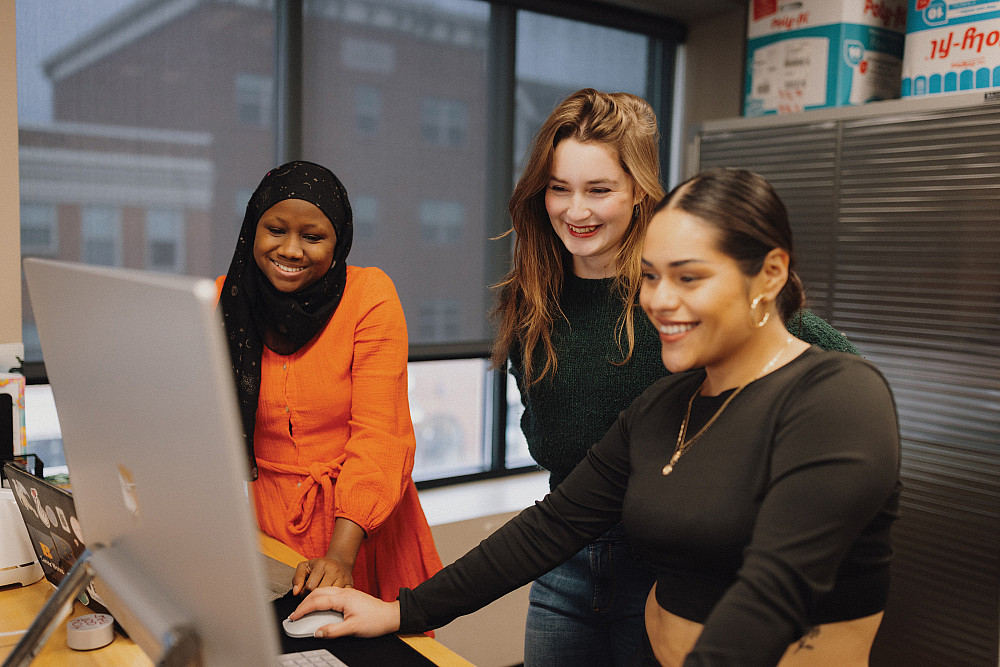 Maker Lab supervisor Fatumata Kaba'24 assisting India Clizer'24 and Frances Donis'24 with their artwork for a totebag project.