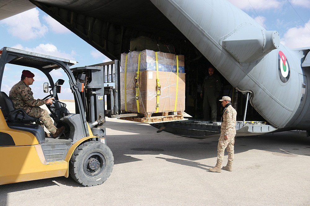 Crew loads crates filled with meals onto a C-130.