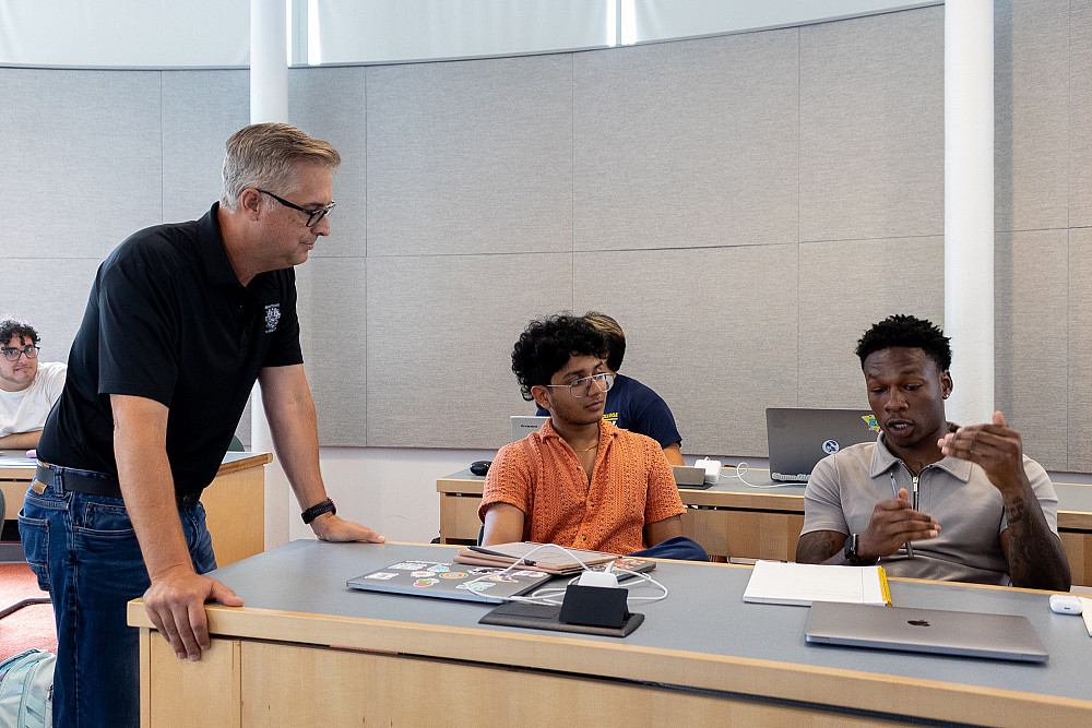 Matt Laszlo'92 speaks with two students in his marketing class.