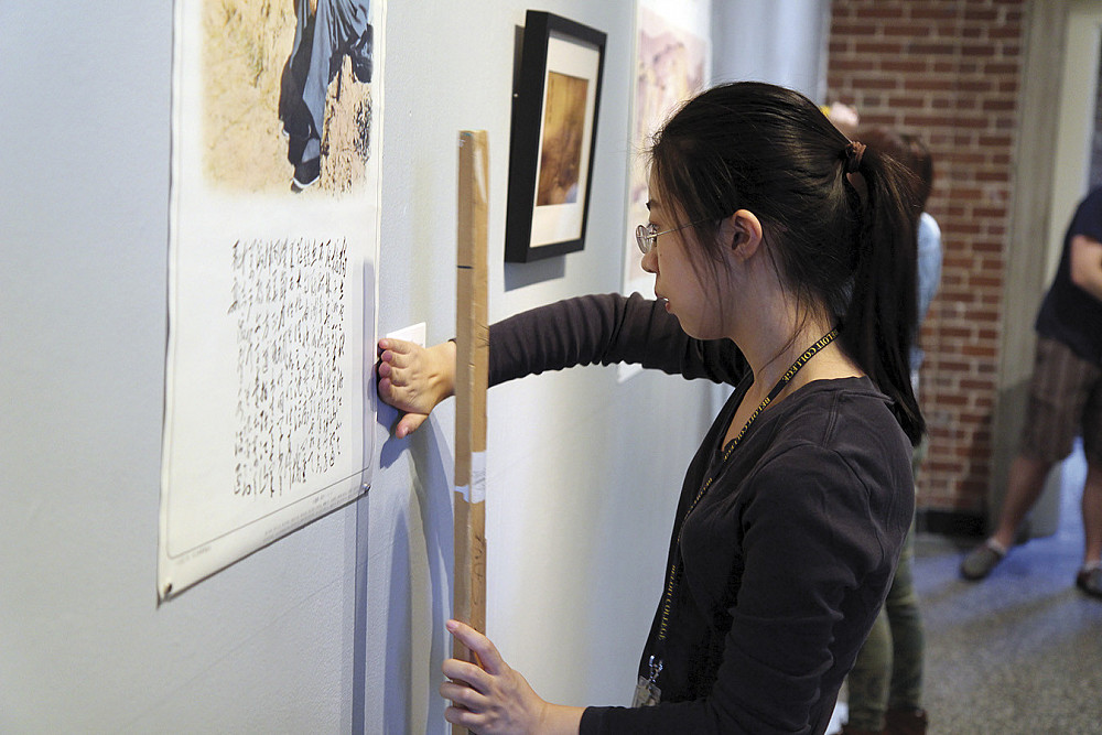In the Neese Gallery of the Wright Museum of Art, Gaizi Jie'15 installs a propaganda poster featuring Chairman Mao sitting alongside...