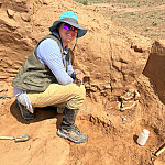 Kiernyn Orne-Adams ’16 poses with a Protoceratops skull (and its toy likeness) in the Gobi Desert.