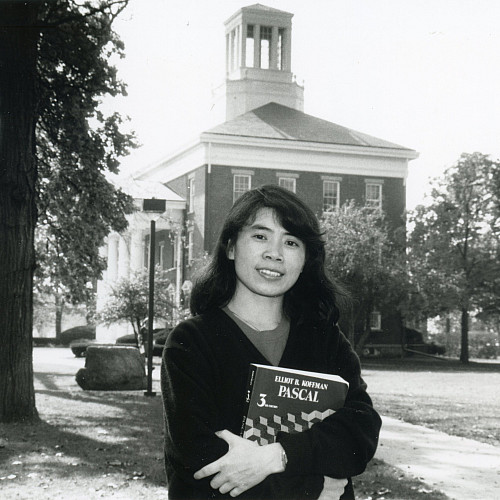 Ying Pang'90, shown in 1989, stands in front of Middle College holding a computer science textbook.