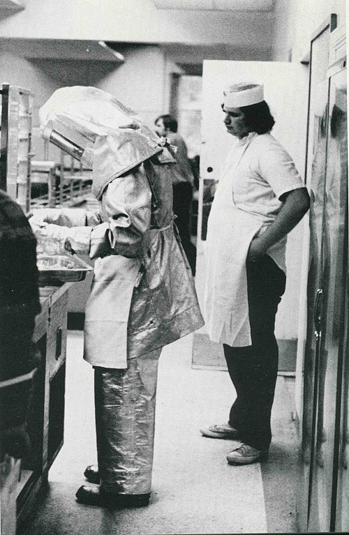 Basic Elmo, Len Pagliaro'76, nonchalantly serves food in Commons while wearing an aluminized crash suit.