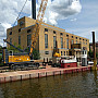 A crane floats on a barge on the Rock River next to the Powerhouse.